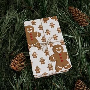 May include: A white gift wrap with a repeating pattern of gingerbread men. The gingerbread men are brown with white icing and red buttons. The gift is tied with twine.