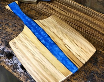 Serving board with handle made of rustic olive wood and blue epoxy resin