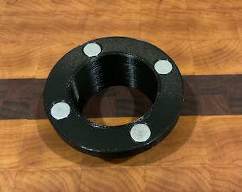 May include: A black plastic ring with four silver magnets attached to the outer edge. The ring has a threaded hole in the center.