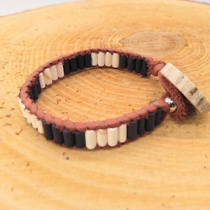 May include: A brown leather bracelet with black and white beads and a wooden toggle clasp.