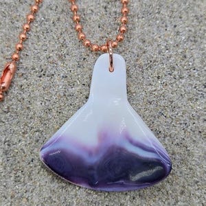 May include: A pendant necklace featuring a smooth, fan-shaped piece of white and purple glass suspended from a copper-toned ball chain. The glass pendant has a glossy finish with a gradient transition from white at the top to deep purple at the base.