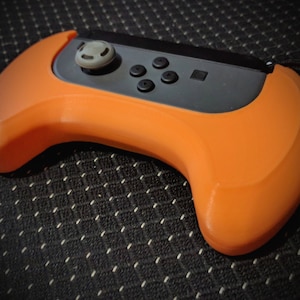 May include: Orange and black Nintendo Switch Joy-Con controller with a protective case.
