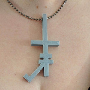 May include: A silver chain necklace with a gray, 3D printed pendant shaped like an inverted cross.