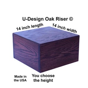 May include: A square, dark oak riser with rounded corners. The product is 14 inches in length and 14 inches in width. The text "U-Design Oak Riser" and "Made in the USA" are visible. The height is customizable.