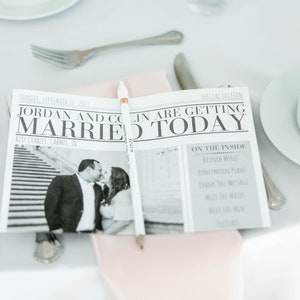 Puede incluir: Un peri&oacute;dico de boda con el titular "Jordan and Colin Are Getting Married Today" se muestra sobre un mantel blanco. El peri&oacute;dico incluye una foto en blanco y negro de la pareja y un l&aacute;piz. Tambi&eacute;n se ven cubiertos y una taza de t&eacute; blanca.