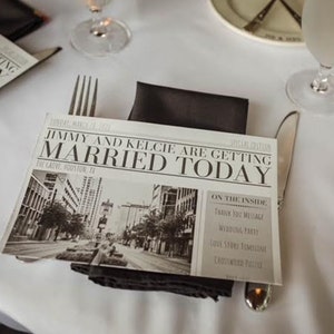 Puede incluir: Un anuncio de boda en blanco y negro dise&ntilde;ado como un peri&oacute;dico. El titular dice "Jimmy and Kelcie are getting Married Today". El anuncio incluye una foto de una calle de la ciudad.