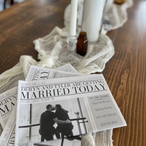 Puede incluir: Programas de boda con dise&ntilde;o de peri&oacute;dico, con el titular "Deryn and Tyler are getting married today" y una foto de la pareja. Est&aacute;n sobre una mesa de madera con un camino de mesa blanco, velas y una peque&ntilde;a botella marr&oacute;n.