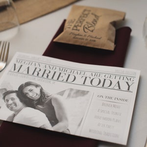 Puede incluir: Una mesa de recepci&oacute;n de bodas con un anuncio estilo peri&oacute;dico que dice "MEGHAN AND MICHAEL ARE GETTING MARRIED TODAY". La mesa tambi&eacute;n incluye un peque&ntilde;o paquete de caf&eacute;, cubiertos y copas de vino.