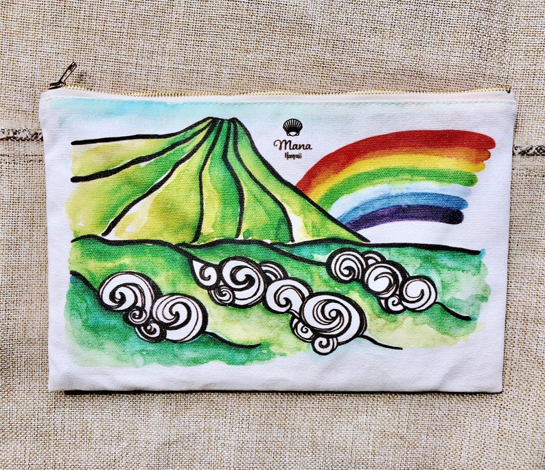 May include: A white canvas zippered pouch with a watercolour illustration of a green mountain with a rainbow over it. The text "Mana Hawaii" is printed in black on the pouch.