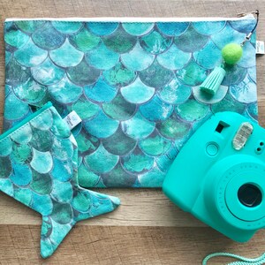 May include: A teal blue mermaid scale patterned zippered pouch with a matching teal blue mermaid tail pouch and a teal blue instant camera with a white strap.