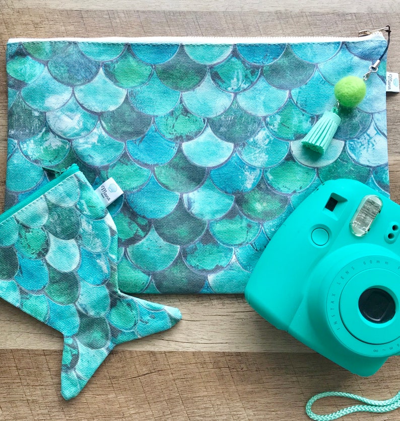 May include: A teal blue mermaid scale patterned zippered pouch with a matching teal blue mermaid tail pouch and a teal blue instant camera with a white strap.