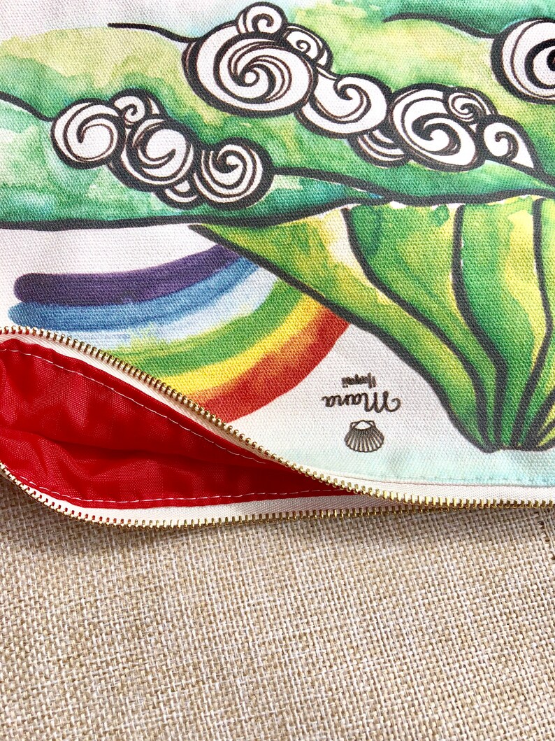 May include: A white canvas zippered pouch with a colourful rainbow design and green leaves with swirls. The pouch is lined with red fabric and has a small shell logo that says "little mermaid".