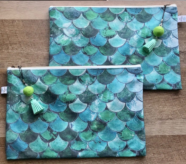 May include: Two zippered pouches with a mermaid scale pattern in shades of green and blue. Each pouch has a green tassel charm.
