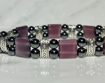 May include: A purple and black beaded bracelet with silver accents. The bracelet is made with round black beads and rectangular purple beads.