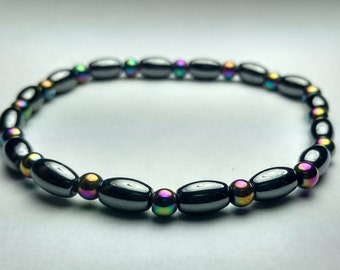May include: A black bracelet with oval-shaped beads and iridescent round beads. The bracelet is made of hematite.