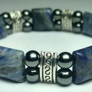 May include: A blue and silver bracelet with square blue stones and round silver and black beads.