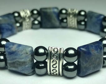 May include: A blue and silver bracelet with square blue stones and round silver and black beads.