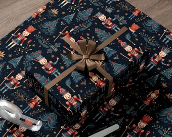 May include: A dark blue gift wrap with a repeating pattern of nutcracker soldiers, Christmas trees, and gold stars. A brown gift box with a brown bow is on top of the wrapping paper. A pair of silver scissors is on the wrapping paper.