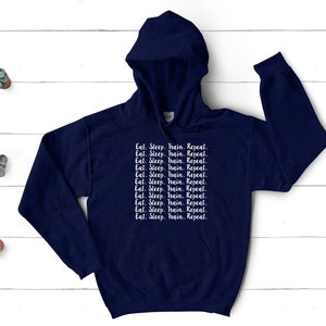 May include: A navy blue hoodie with a white print that reads "Eat. Sleep. Train. Repeat." repeated multiple times.