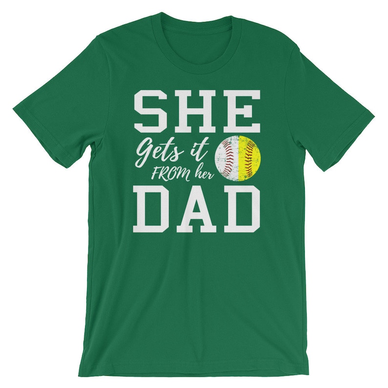 May include: Green t-shirt with white text that reads "SHE gets it FROM her DAD" and a yellow softball graphic.