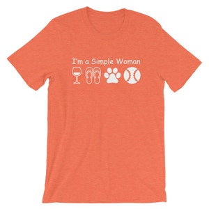 May include: Orange short-sleeved t-shirt with the text "I'm a Simple Woman" and white icons of a wine glass, flip-flops, a paw print, and a baseball.