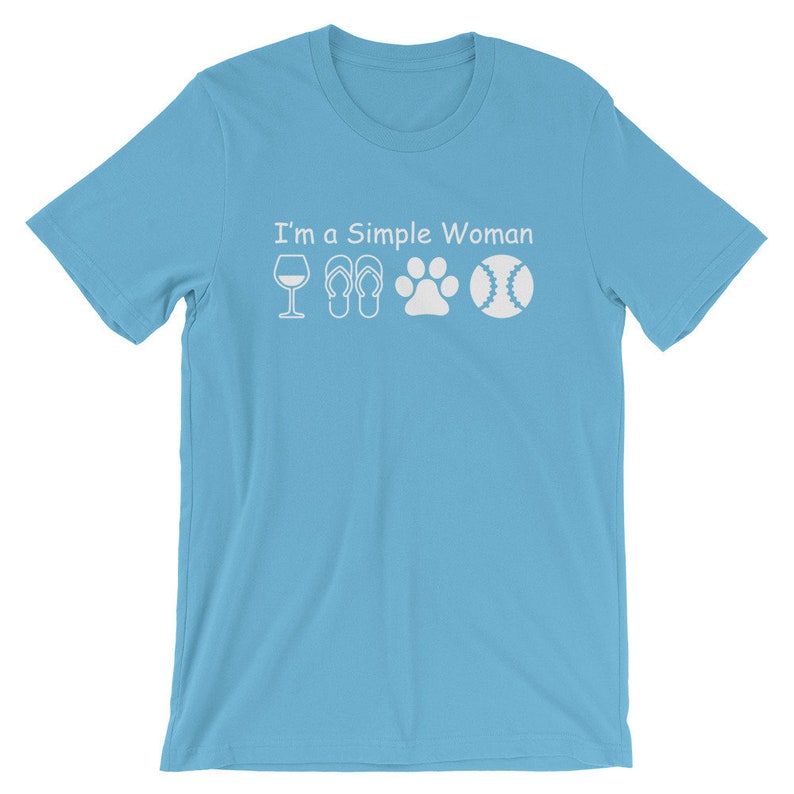 May include: A light blue t-shirt with the text "I'm a Simple Woman" and white icons of a wine glass, flip flops, a paw print, and a baseball.