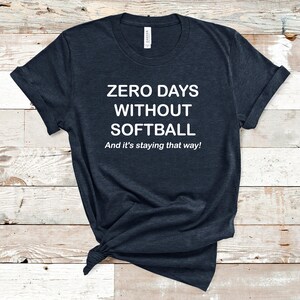 May include: A dark blue t-shirt with white text that reads "ZERO DAYS WITHOUT SOFTBALL And it's staying that way!"