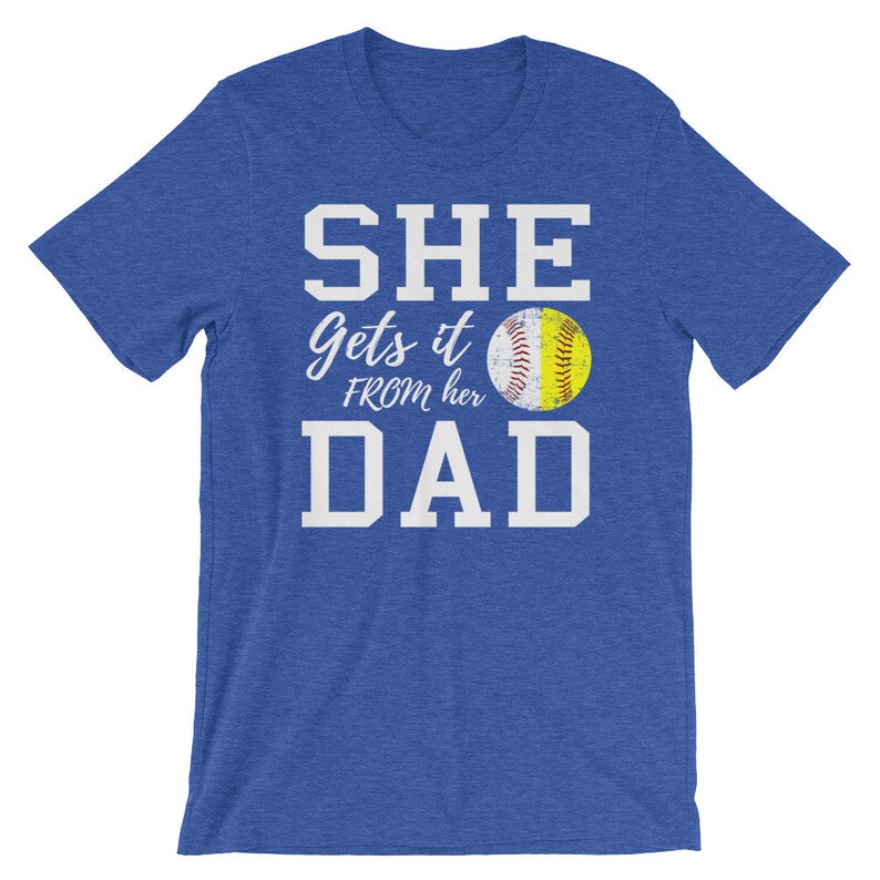 May include: Blue t-shirt with white text that reads "SHE gets it FROM her DAD" and a yellow softball graphic.