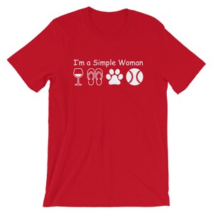 May include: Red short-sleeved t-shirt with white text that reads "I'm a Simple Woman" and four white icons: a wine glass, flip-flops, a paw print, and a baseball.