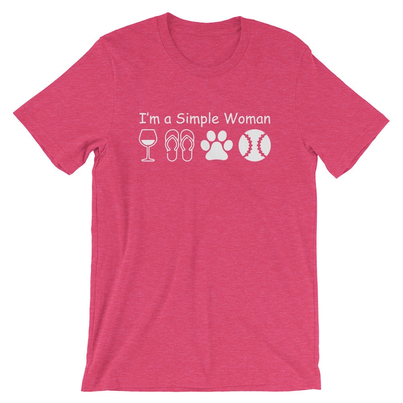 May include: Pink short-sleeved t-shirt with the text "I'm a Simple Woman" and white icons of a wine glass, flip flops, a paw print, and a baseball.