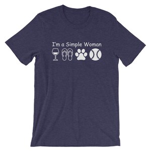 May include: A navy blue t-shirt with the text "I'm a Simple Woman" and white icons of a wine glass, flip flops, a paw print, and a baseball.