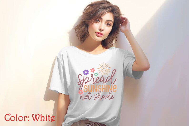 May include: White t-shirt with a graphic design that says "Spread Sunshine not Shade" with a sun and flowers in colorful hues.