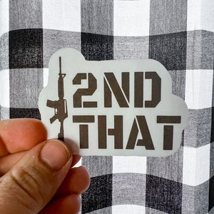 May include: A white sticker with a black silhouette of a rifle and the text "2ND THAT" printed on it.