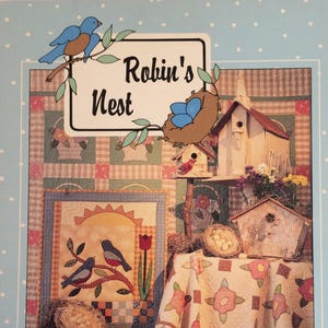 May include: A book cover titled "Robin's Nest" with a collage of birdhouses, nests, and a quilt with floral patterns. The cover includes illustrations of birds, eggs, and foliage, with a light blue polka-dot border.