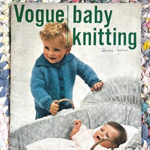 May include: A vintage "Vogue baby knitting" magazine cover. It shows a toddler in a blue knitted cardigan and a baby in a bassinet. The cover has green text and the number "9" and price "2/6".