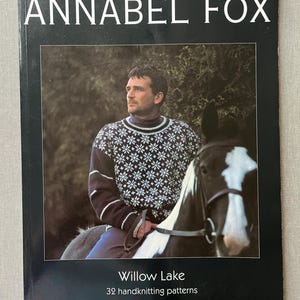 May include: A book cover featuring the title "ANNABEL FOX" in white. The image depicts a person in a patterned sweater on horseback. The text "Willow Lake" and "32 handknitting patterns" are displayed below the image.
