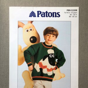 May include: A knitting pattern for a green jumper with a white sheep design. The pattern is called "Shaun the Sheep" and is for children aged 6-13 years old. The pattern is from Patons and has the number PBN E2208.