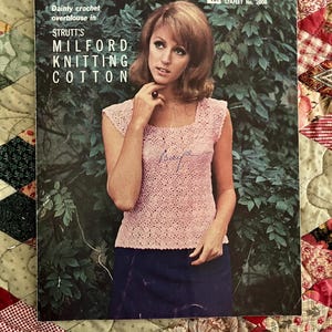 May include: A vintage knitting pattern leaflet for a crochet overblouse. The leaflet features a model wearing a pink crochet top and a dark blue skirt. The text on the leaflet reads "Dainty crochet overblouse in Strutt's Milford Knitting Cotton 15c Leaflet No. 2008".