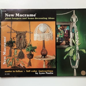 May include: A book titled "New Macrame" with a brown cover and a photo of a macrame plant hanger on the front. The book features plant hangers and home decorating ideas with full colour instructions by Lynn Paulin.