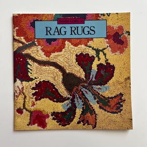 May include: A book titled "Rag Rugs" with a colourful floral design on the cover. The book is part of a series called "Needle Crafts 10".