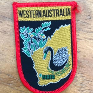 May include: Embroidered patch with "WESTERN AUSTRALIA" text above a map outline. It features a black swan, green foliage, and "PERTH". The patch has a red border.