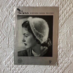 May include: A vintage knitting pattern book cover featuring a woman wearing a white knitted hat. The cover is silver with black text that reads "Patons Knitting Book No. 289" and "9d."