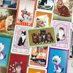 May include: A collection of vintage cat-themed playing cards. The cards feature various cat illustrations in different poses and colors, including orange, black, white, and gray. Some cards have decorative borders and backgrounds, creating a charming and nostalgic aesthetic.