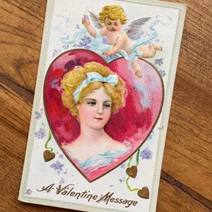 Antike Valentinstag Postkarte mit roten und goldenen Herzen, blauen Schleifen und einem Engelchen