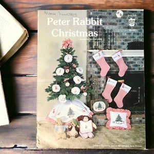 May include: A vintage book cover titled "Peter Rabbit Christmas" with a Christmas tree illustration. The cover features a Christmas tree, ornaments, and stockings. The book is by Beatrix Potter Creations.