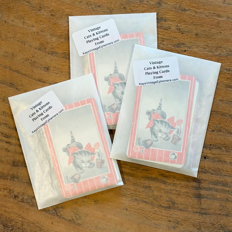 May include: Three packs of vintage playing cards featuring a kitten illustration with a red bow and a small pot. Each pack is sealed in a white paper envelope with a label that reads "Vintage Cats & Kittens Playing Cards From KaysVintageEphemera.com."