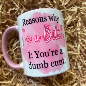 May include: White ceramic mug with a pink handle and interior. The mug features the text "Reasons why I'm a Bitch" in black and pink, with the number 1 and the text "You're a dumb cunt."