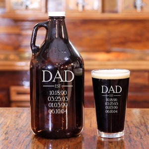 May include: A brown glass growler and a clear glass pint glass, both engraved with the word "DAD" and a list of dates. The growler has a white lid and a handle.