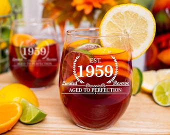 May include: Two stemless wine glasses filled with red wine and fruit. The glasses are etched with the text "EST. 1959 Limited Reserve Aged to Perfection".