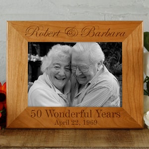 May include: A wooden picture frame with a black and white photo of an older couple. The frame is engraved with the text "Robert & Barbara 50 Wonderful Years April 22, 1969".